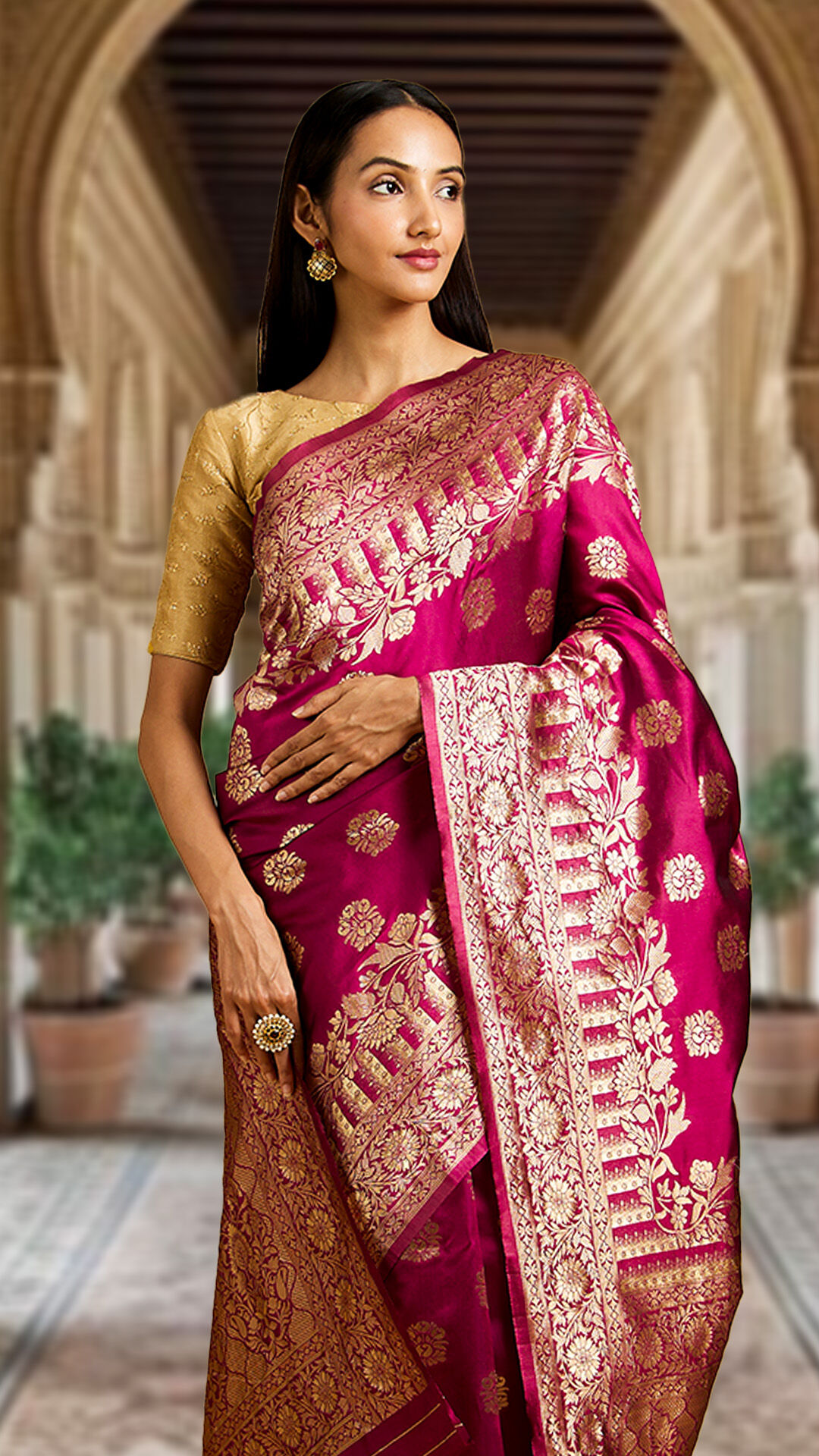 A lady flaunting a pink silk saree and gold earrings